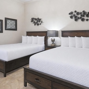 This guest bedroom features two queen beds, stylish decor, and soft lighting for a restful stay
