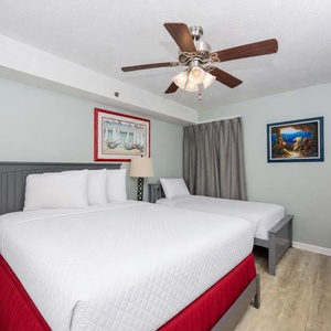 This guest bedroom features two comfortable beds, a full and twin, vibrant artwork, and a TV for your entertainment