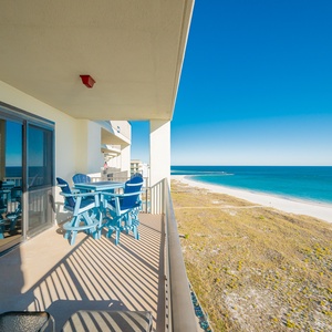 Spacious balcony features blue seating and offers a breathtaking view of the beach and vibrant gulf waters