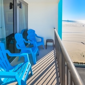 Relax on the balcony in bright blue chairs, enjoying stunning beachfront views and the gentle sound of waves