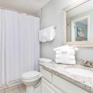 Refresh in this sleek bathroom featuring a spacious vanity, fluffy towels, and a relaxing tub-shower combination