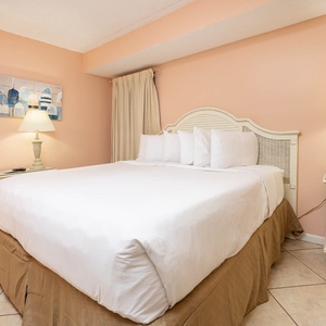 Guest bedroom featuring a plush king-size bed, soft peach walls, and charming coastal decor for a relaxing getaway