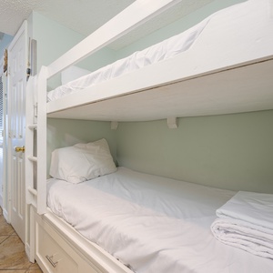 This cozy bunk area features white bedding and a playful sign, perfect for kids' adventures during their stay