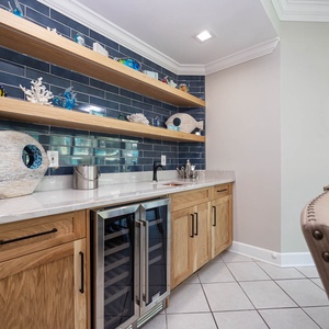 Grab a chilled bottle of wine from the cooler at the wet bar while admiring the charming coastal decor and vibrant accents