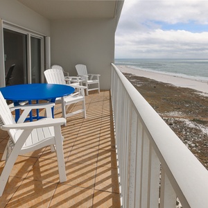 Enjoy a relaxing moment on the balcony with a blue table and white chairs, overlooking the beautiful beachfront view