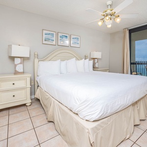 Bright and airy master bedroom featuring a king bed, coastal decor, and a balcony with views of the gulf