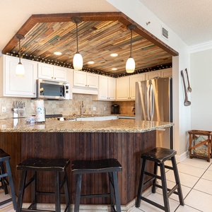 Gather around this elegant kitchen, featuring sleek granite countertops, stylish pendant lighting, and stainless appliances