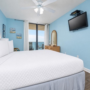 Bright blue walls and a cozy king bed create a serene atmosphere in the master suite, complemented by a beachfront balcony