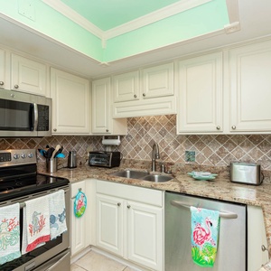 Bright and inviting kitchen featuring stainless appliances, granite countertops, and colorful beach-themed towels