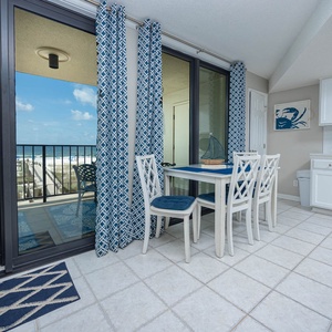 This dining area features a bright table set against vibrant blue curtains, with a lovely view of the beach just outside