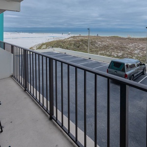 Relax on the balcony with vibrant blue chairs, overlooking the pristine beach and tranquil waters beyond