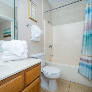 Experience a bright bathroom with a spacious vanity, fresh towels, and a relaxing shower area for your comfort