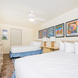 Inviting guest bedroom featuring two queen beds, a TV, and vibrant coastal decor for a relaxing stay