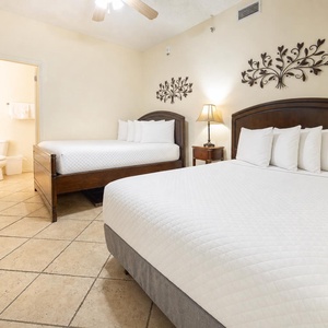 Guest bedroom featuring two double beds, a bedside lamp, and decorative wall accents, creating a welcoming atmosphere