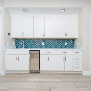 Prepare drinks at the wet bar with a vibrant backsplash, stainless appliances, and sleek cabintery