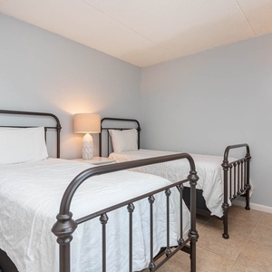 This guest bedroom features two twin beds, soft lighting, and a serene atmosphere for a restful getaway