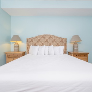 Master bedroom featuring a king bed, elegant lamps, and soothing blue walls for a relaxing getaway