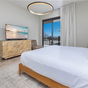 Relax in this master bedroom featuring a king bed, a stylish dresser, and sliding doors with outdoor patio views