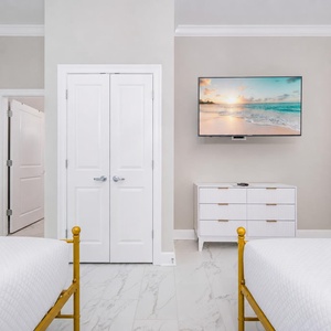 Relax in this cozy guest bedroom featuring two queens, a TV for entertainment, and soft bedding