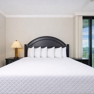 Relaxing guest bedroom featuring a plush king bed, cozy seating, and large windows offering a scenic view