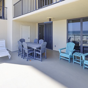 Relax on the spacious patio with turquoise chairs and a dining table, enjoying the beautiful coastal view