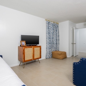 This guest bedroom features a convenient sleeping arrangement, TV, and a cozy atmosphere enhanced by blue accents