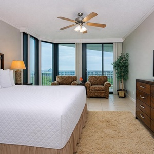 Master bedroom featuring a king-sized bed, cozy seating area, and large windows with a lovely view