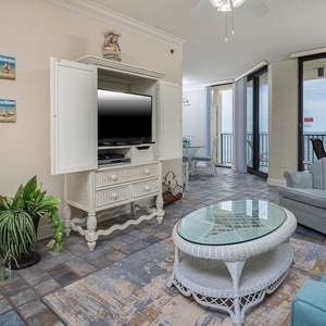 Living area features a light blue sofa with a queen sleeper, a glass coffee table, and a view of the beach from the balcony