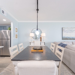 A serene dining area invites you to enjoy meals and conversations surrounded by soft blue walls and coastal art