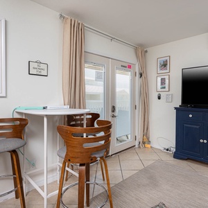 This cozy living area features a large TV, stylish bar stool seating area, and easy access to the outdoor space