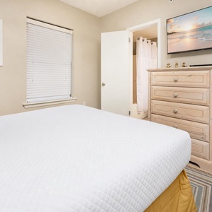 Experience restful nights in this inviting guest bedroom featuring a plush queen bed, a TV, and colorful decor