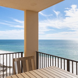 Enjoy breathtaking views of the tranquil beach and sparkling waters from the private balcony with a wooden dining set