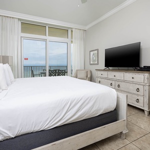 Cozy master suite with a king bed, a large TV, and sliding doors leading to a balcony with beautiful views