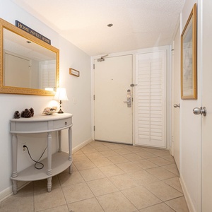 Welcoming entryway features a decorative mirror, soft lighting, and a charming console table with pinecones and seashells
