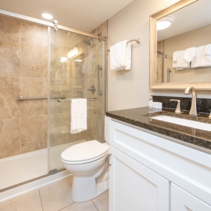 This bathroom features elegant granite countertops, a spacious glass shower, and soft towels for a refreshing experience