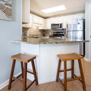 Gather around the granite counter with two stools, perfect for casual meals in a welcoming kitchen space