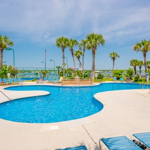 Relax by the pool surrounded by palm trees, with inviting lounge chairs and a serene view for a perfect getaway