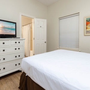 Inviting guest bedroom featuring a comfortable queen bed, a TV for entertainment, and natural light from the window