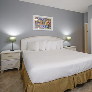 The guest bedroom features a plush queen bed, stylish lamps, and colorful artwork, perfect for a restful getaway