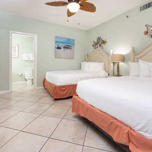Inviting guest bedroom with two comfortable queen beds, coastal decor, and easy access to the bathroom