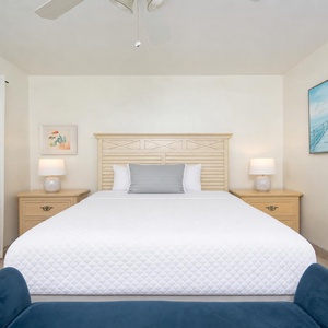 Guest bedroom featuring a queen bed, soft white linens, and coastal decor with natural light from sheer curtains