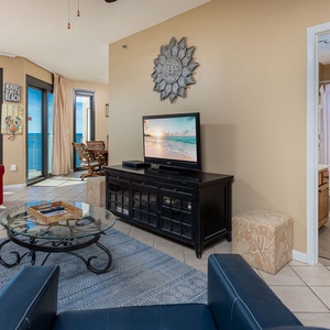 Inviting living space with a large TV, comfortable seating, and views of the tranquil beach beyond
