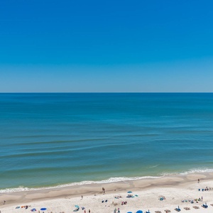 Serene beach with soft white sand and gentle waves under a clear blue sky, perfect for relaxation
