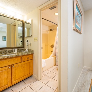 The master bath features a granite countertop, ample towels, and shower with a colorful curtain, creating a fresh atmosphere