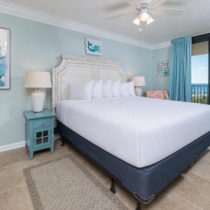 Relax in this serene master bedroom featuring a king bed, coastal decor, and a view of the beach