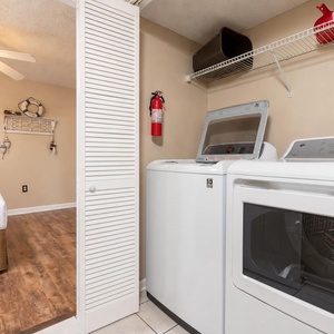 Laundry area featuring a washer and dryer, with a view into a cozy guest bedroom and decorative nautical accents