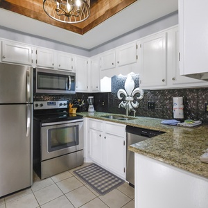 This kitchen features stainless appliances, granite countertops, a stylish backsplash, and a convenient coffee maker