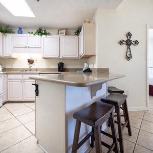 Bright kitchen area features light cabinetry, a breakfast bar with seating, and white appliances