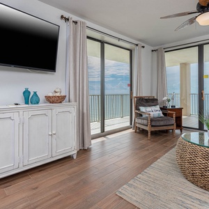 This inviting living area features a large TV, stylish decor, and a breathtaking beachfront view from the sliding glass doors