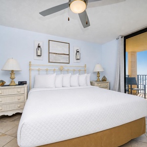 Brightly decorated master bedroom featuring a king bed, elegant nightstands, and a balcony offering a breathtaking beach view